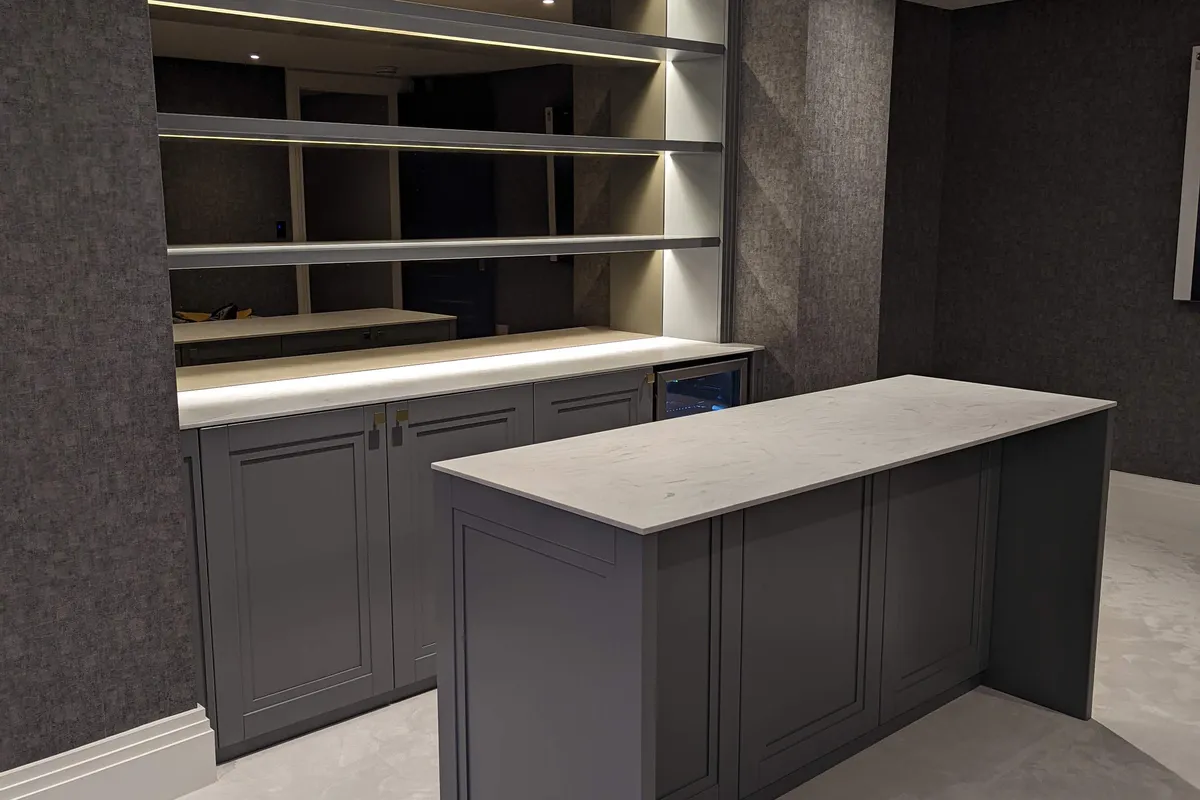 Bespoke home bar with slate grey shaker cabinetry, mirrored back-lit shelving, marble worktop and matching island with integrated wine fridge